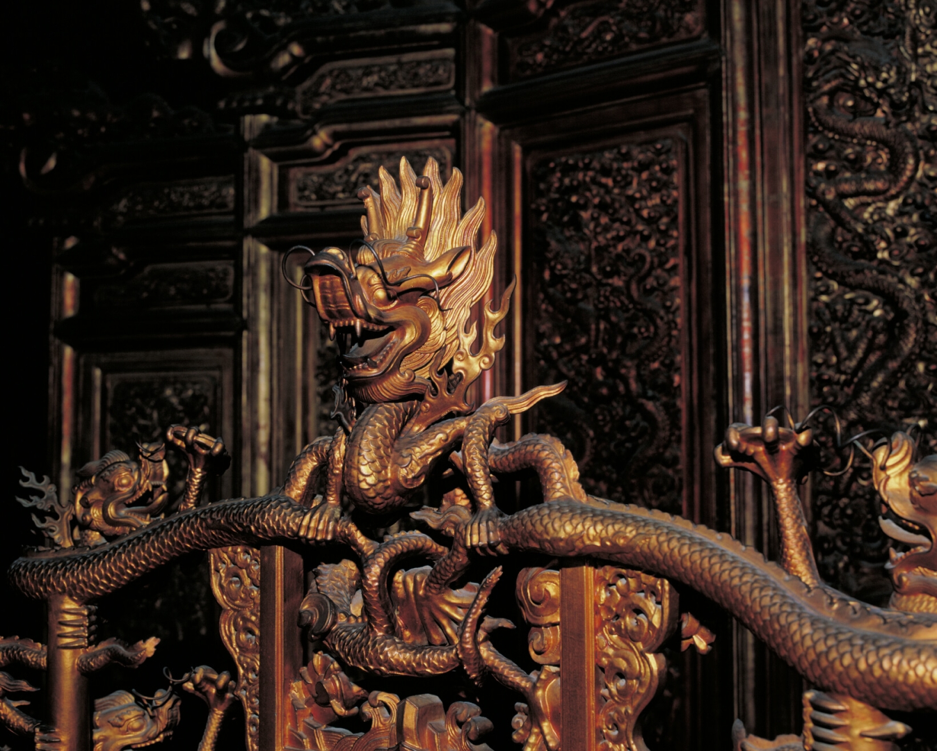 Золотые колонны с <br />
обвивающим их драконом <br />
и внутреннее убранство в <br />
Зале Высшей Гармонии – голова <br />
дракона на спинке трона